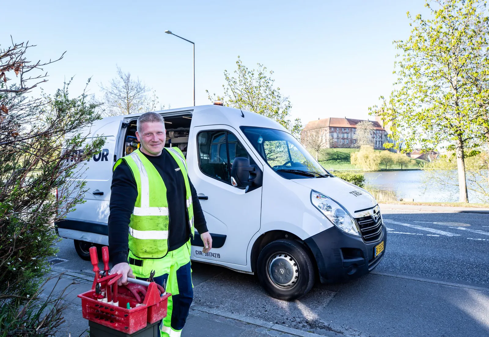 Service technician smiling beside a work van with a toolbox.